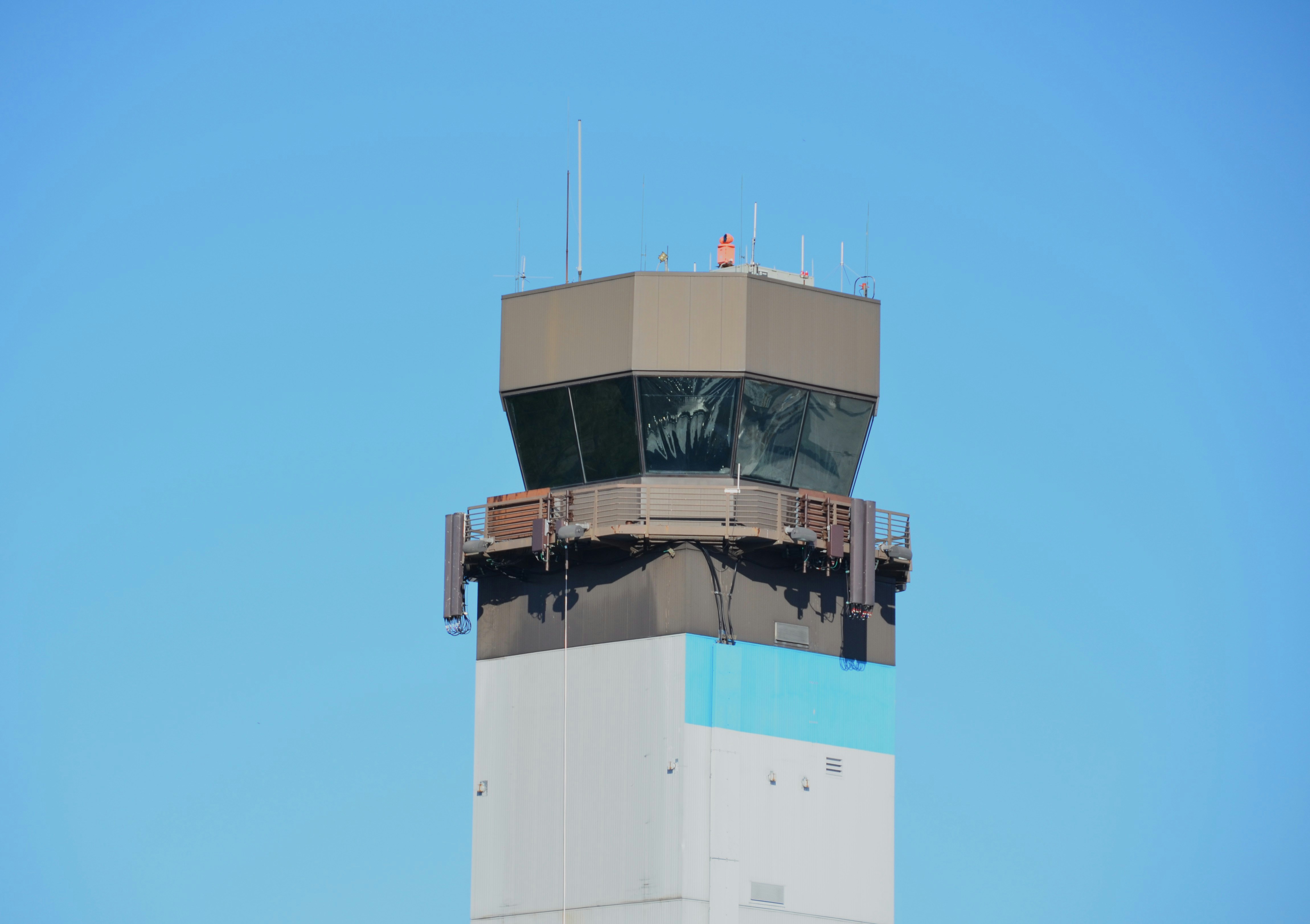 An air traffic control tower against a clear blue sky